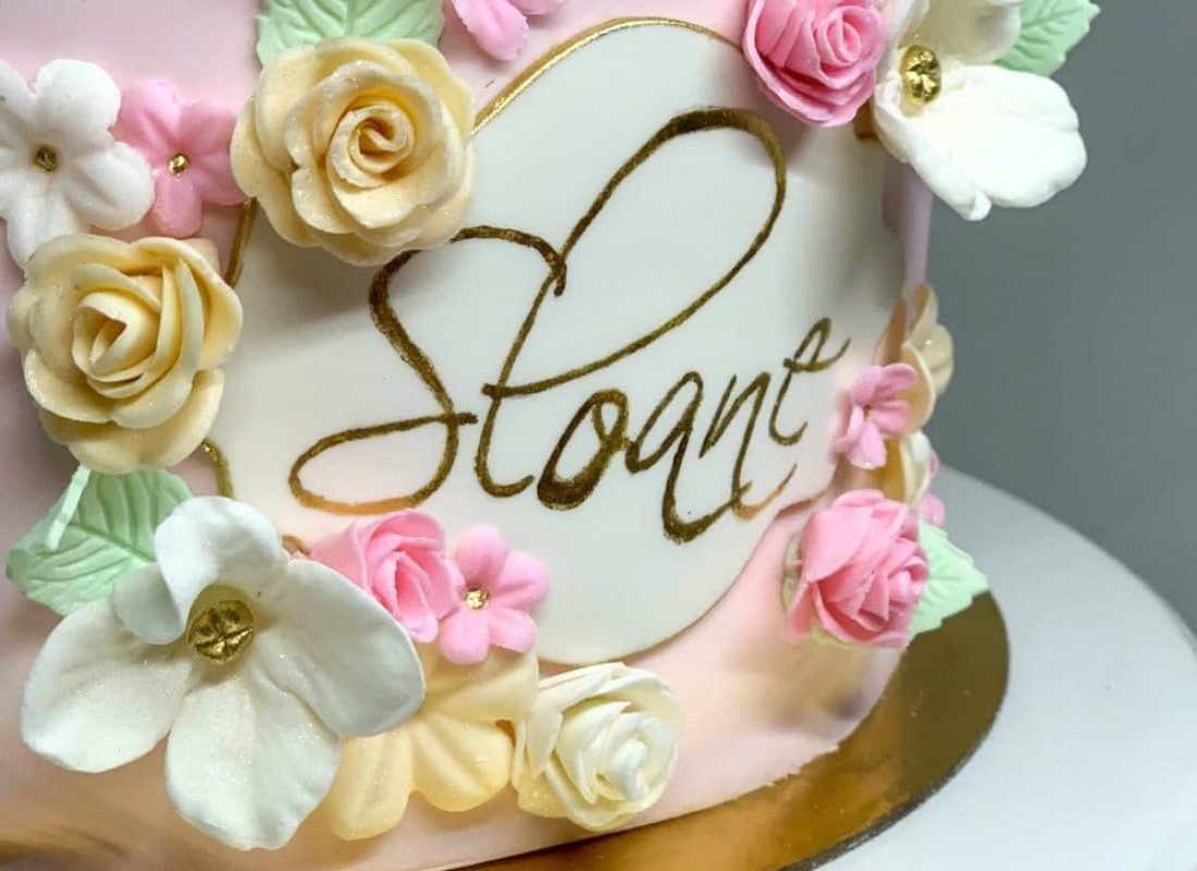 Baker assembling a multi-tiered custom cake with handcrafted sugar flowers for a Pearland, TX wedding reception