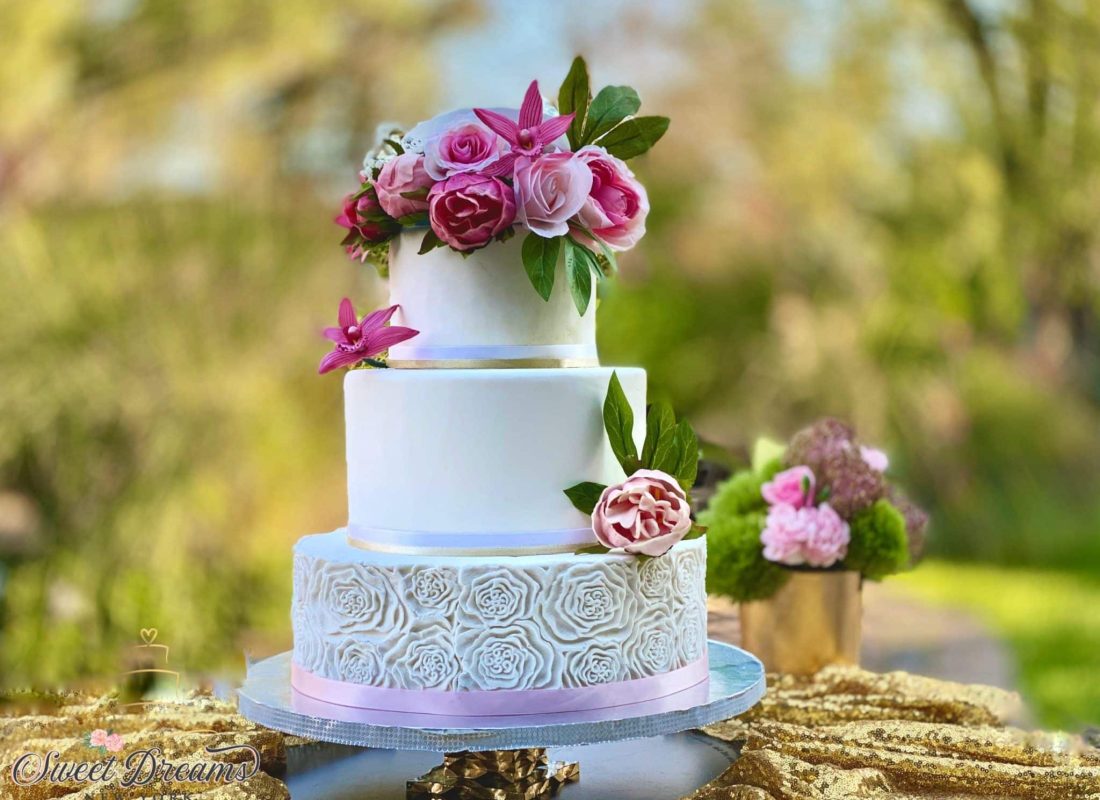 Bakery chef adding intricate floral details to a large custom wedding cake for a Houston event venue