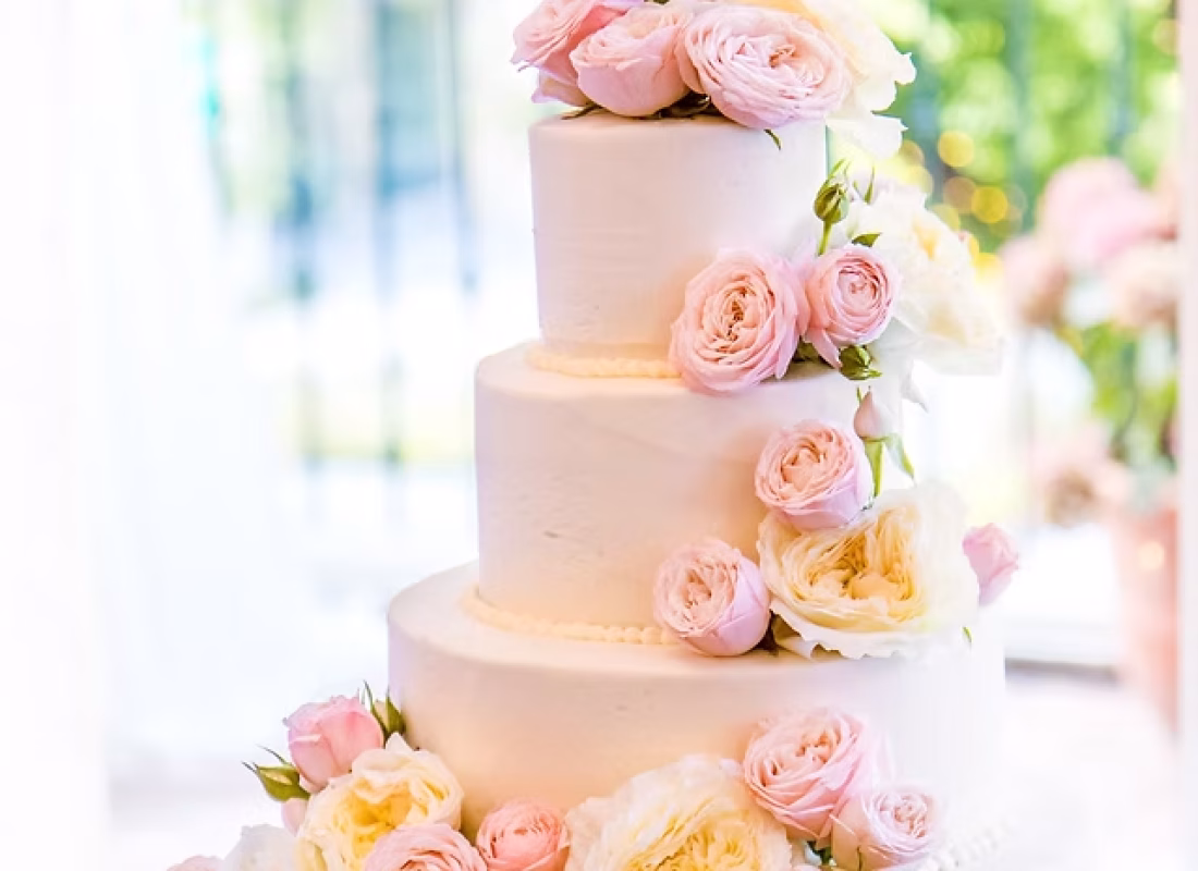Cake artist adding hand-formed sugar florals to a wedding cake at a League City, TX reception venue