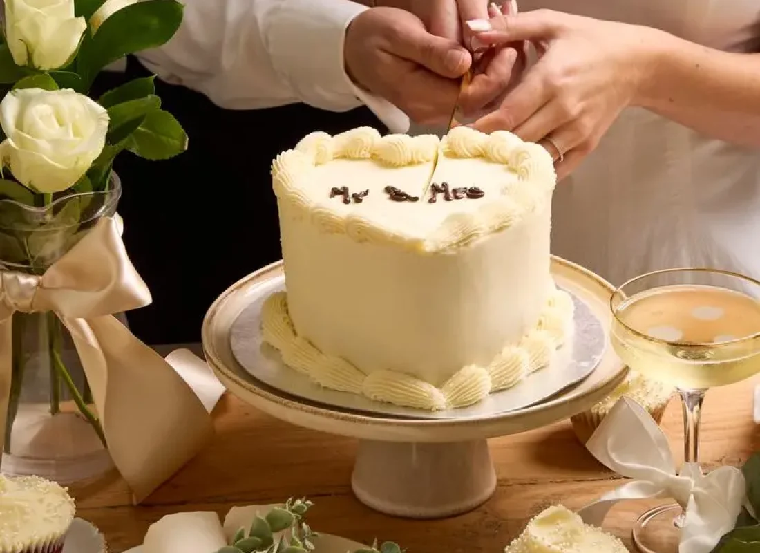Cake artist adding hand-formed sugar florals to a wedding cake at a League City, TX reception venue